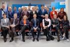 Ludzie siedzą i stoją na scenie.