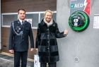 Iwona Gibas z zarządu województwa wraz z szefem OSP Zator, stojący obok nowoczesnego defibrylatora zamontowanego przed wejściem do remizy