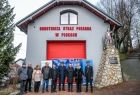 Uczestnicy uroczystego przekazania strażackiego sprzętu stojący przed remizą OSP Płoki 
