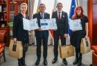 Wicemarszałek Witold Kozłowski z trojgiem osób trzymających wyróżnienia w dłoniach.