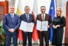 Wicemarszałek Witold Kozłowski i wójt Grybowa prezentujący umowy. Obok mężczyzna i kobieta.