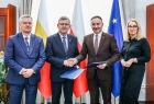 Wicemarszałek Witold Kozłowski i wójt Grybowa w uścisku dłoni. Obok mężczyzna i kobieta. 