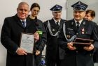 Wicemarszałek Ryszard Pagacz trzyma w rękach dyplom. Obok stoi strażak.
