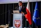 Marszałek Łukasz Smółka stoi przy mównicy.