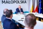 Wicemarszałek Ryszard Pagacz siedzi z beneficjentami przy stole.