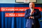 Wicemarszałek Ryszard Pagacz stoi na sali w szkole z mikrofonem.