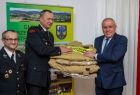 Wicemarszałek Ryszard Pagacz przekazuje strażakowi mundury. Obok stoi drugi strażak.