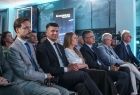 Marszałek Łukasz Smółka siedzi na widowni. Obok inni ludzie.