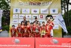 Grupa zawodników w czerwonych strojach przed wejściem na podium.