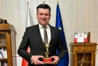 Łukasz Smółka prezentuje nagrodę - statuetkę