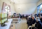 Koncert w kaplicy cmentarnej. Na pierwszym planie siedzą ludzie.