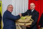 Wicemarszałek Ryszard Pagacz przekazuje strażakowi mundury i podaje mu rękę.