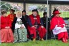 Ludzie w strojach historycznych siedzą pod namiotem.