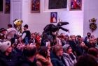 Kolędnicy w strojach ludowych idą przez kościół.
