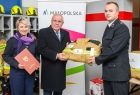 Wicemarszałek Ryszard Pagacz podaje mundur strażakowi. Obok stoi kobieta, która trzyma w rękach teczkę.