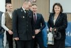 Jadwiga Wójtowicz trzyma strażacki sprzęt. Obok stoją mężczyźni.