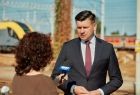 Marszałek Łukasz Smółka stoi przed kobietą z mikrofonem w ręce.