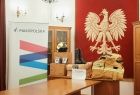 Sala ślubów Urzędu Gminy w Przeciszowie. Na tle dużego godła Polski ustawione są pakunki ze strażackim sprzętem. Między innymi mundur polowy, kask strażacki oraz buty