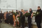 Uczestnicy upamiętnienia stojący z kwiatami i wieńcami przed nagrobnym pomnikiem 