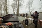 Uczestnicy upamiętnienia stojący z kwiatami i wieńcami przed nagrobnym pomnikiem oraz prowadząca uroczystość Agnieszka Molenda-Kopijasz z Fundacji Pobliskie Miejsca Pamięci Auschwitz-Birkenau