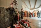 Warta wojskowa, dwie dziewczyny w mundurach z bronią, przed tablicą poświęconą Żołnierzom Wyklętym