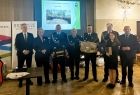 Pamiątkowa wspólna fotografia. Iwona Gibas z Zarządu Województwa Małopolskiego, wojewoda małopolski Krzysztof Jan Klęczar, burmistrz gminy Brzeszcze Radosław Szot oraz strażacy ochotnicy z gminy Brzeszcze