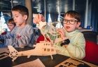 dwóch chłopców w wieku szkolnym buduje model śmigłowca ze sklejki