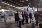 Goście z Mołdawii stoją w jednym z hangarów Muzeum Lotnictwa Polskiego w Krakowie. Na drugim planie stoi pomalowany na szaro Junkers 52, niemiecki samolot transportowy skonstruowany w wytwórni Junkers w latach 30. dwudziestego wieku.