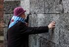 Jedna z Ocalałych, dotykająca Ściany Śmierci w byłym niemieckim obozie zagłady Auschwitz