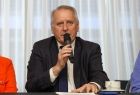 Radny i przewodniczący Małopolskiej Organizacji Turystycznej Grzegorz Biedroń przy stole konferencyjnym, z mikrofonem w ręku.