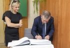 Wicemarszałek Witold Kozłowski podpisuje księgę. Obok radna Sylwia Żak-Biesik.
