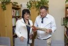 Radni Danuta Kawa i Krzysztof Nowak czytający książkę w bibliotece.