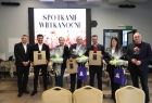 Iwona Gibas z Zarządu Województwa Małopolskiego, poseł Andrzej Adamczyk, starosta olkuski Bogumił Sobczyk, wicestarosta Rafał Czeladzki, burmistrz Wolbromia Radosław Kuś i wiceburmistrz Dominika Bugaj. Za nimi ekran z napisem Spotkanie Wielkanocne