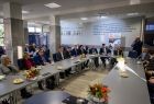Grupa osób przy długim okrągłym stole.