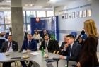 Poseł Anna Pieczarka przemawia do mikrofonu. Obok mężczyźni siedzący przy stole.