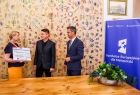 Iwona Gibas z Zarządu Województwa Małopolskiego wręcza dwóm przedstawicielom miechowskiego samorządu symboliczny czek