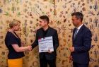 Iwona Gibas z Zarządu Województwa Małopolskiego wręcza przedstawicielom miechowskiego samorządu symboliczny czek