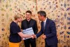 Gratulacje, podziękowania i uścisk dłoni. Iwona Gibas z Zarządu Województwa Małopolskiego wręcza dwóm przedstawicielom miechowskiego samorządu symboliczny czek