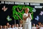 Iwona Gibas z zarządu województwa zwraca się do uczestników wydarzenia. Za panią marszałek siedzą dzieci, które przygotowały program artystyczny. W tle, na ścianie, znajduje się makieta drzewa, a nad nim napis: Im głębsze korzenie tym mocniejsze drzewo
