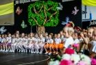 Kilkadziesiąt małych dziewczynek siedzących obok siebie w rzędzie i czekających na rozpoczęcie programu artystycznego 