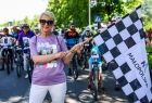 Iwona Gibas z zarządu województwa trzymająca startową flagę w biało-czarną kratę tuż przed rozpoczęciem rajdu rowerowego 