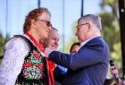 Wicemarszałek Witold Kozłowski przypina odznakę kobiecie w stroju regionalnym.