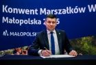 Marszałek Małopolski Łukasz Smółka siedzący przy stole. 