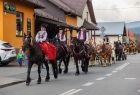 Ludzie w strojach regionalnych jadący na koniach.