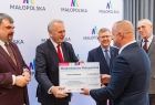 Radny Grzegorz Biedroń wręcza czek beneficjentowi. 