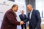 Poseł Patryk Wicher wręcza czek beneficjentowi.