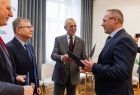 Radny Jan Wiesław Duda wręcza dokument mężczyźnie.