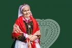 starsza kobieta w stroju regionalnym na tle haftowanego serca