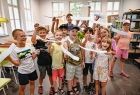 grupa roześmianych dzieci trzyma w rękach modele samolotów z balsy