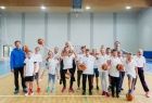 Grupa dzieci w strojach sportowych z piłkami w rękach. 